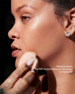 Rihanna applying Fenty Beauty Pro Filt'r Instant Retouch Concealer in shade 290 with makeup sponge. 